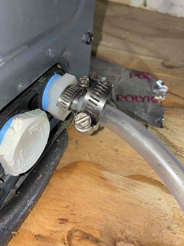 Responded to service call for recurring condensate drain line leak originating from second floor crawl space affecting two floors below. Inspected condensate drainage system and identified compromised connection points in the drain line assembly. Secured PVC pipe fitting to flexible drainage hose using stainless steel hose clamp to eliminate leak at primary connection point. Verified proper drainage flow from air handler drain pan through clear tubing connected to brass drain valve. Tested system operation to confirm leak was resolved and condensate properly evacuating without further water intrusion to lower levels.