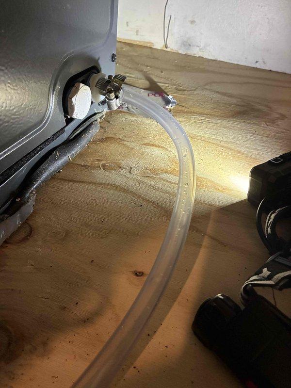 Responded to service call for recurring condensate drain line leak originating from second floor crawl space affecting two floors below. Inspected condensate drainage system and identified compromised connection points in the drain line assembly. Secured PVC pipe fitting to flexible drainage hose using stainless steel hose clamp to eliminate leak at primary connection point. Verified proper drainage flow from air handler drain pan through clear tubing connected to brass drain valve. Tested system operation to confirm leak was resolved and condensate properly evacuating without further water intrusion to lower levels.