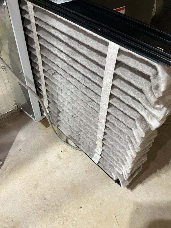 Completed routine cooling system maintenance on residential HVAC unit. Inspected dual pleated air filters showing moderate dust accumulation, examined Goodman furnace system and associated components including water heater, condensate drainage lines, and electrical connections to ensure proper operation ahead of cooling season.