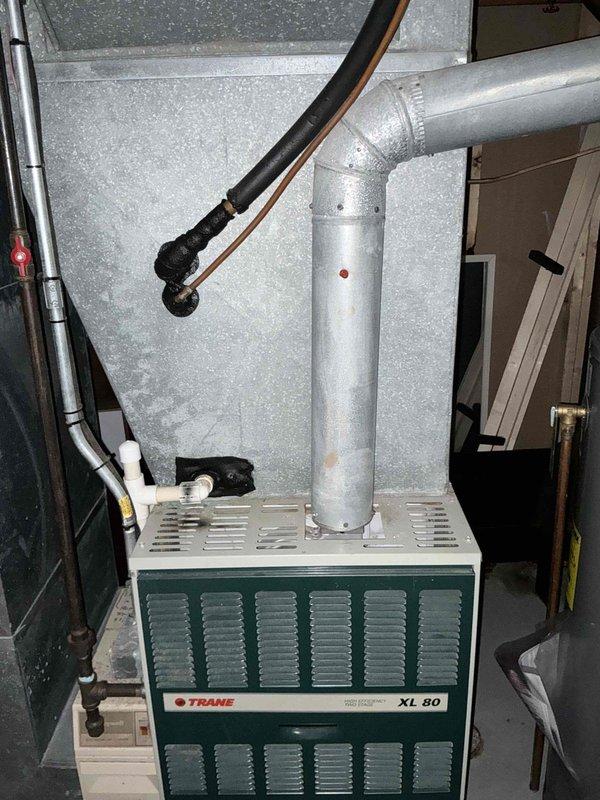 Provided comprehensive estimate for complete HVAC system replacement at residential property with approximately 2,200 square feet. Existing Trane XL 80 furnace and outdoor condensing unit, both installed circa 1998, have reached end of service life with air conditioning system no longer operational as of the previous week. Assessment included evaluation of indoor furnace unit located in basement mechanical room with existing ductwork configuration and outdoor heat pump/AC unit positioned against exterior brick wall with associated refrigerant lines, electrical connections, and condensate drainage systems.