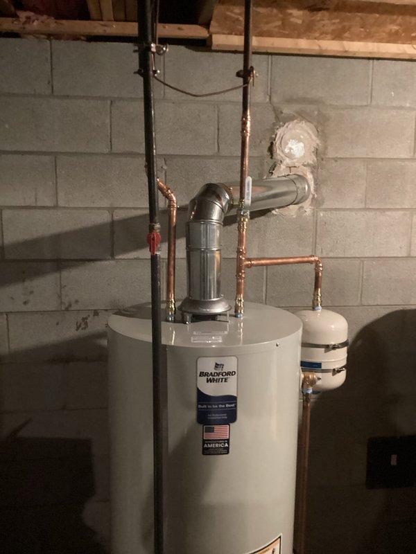 Responded to service call for non-functioning Bradford White tanked water heater with no hot water production. Upon inspection, assessed existing 40-50 gallon conventional tank water heater installation in basement mechanical room, including copper supply lines, PVC venting system through exterior wall, expansion tank, and gas supply connections. Customer expressed interest in converting from traditional tank system to tankless water heater technology. Documented current equipment configuration, plumbing connections, venting arrangement, and available space for potential tankless conversion, photographing existing installation for replacement planning and estimate preparation.