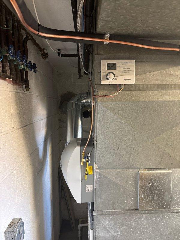 Completed full HVAC system installation in basement mechanical room including 96% efficiency furnace, air conditioning system, and Aprilaire whole-home humidifier. Installed all necessary condensate drain lines using white PVC piping, connected electrical service, mounted humidity control panel on wall with proper wiring, and integrated all components with existing ductwork. System tested and verified operational with all safety labels properly affixed and equipment secured to manufacturer specifications.