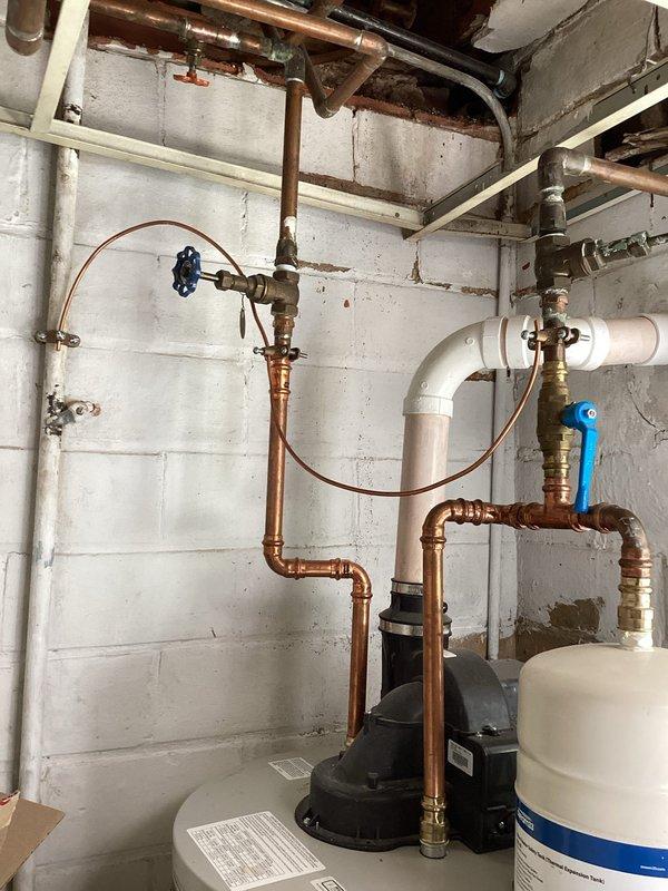 Completed scheduled maintenance flush and fill procedure on residential tanked water heater located in basement utility area. Drained sediment buildup from tank bottom, flushed system thoroughly to remove mineral deposits and debris, then refilled unit to restore proper operation. Inspected all associated plumbing connections, including copper supply lines, brass valves, expansion tank, and circulator pumps. Verified proper function of blue-handled ball valve and all shut-off points. System tested and confirmed operational upon completion of maintenance service.