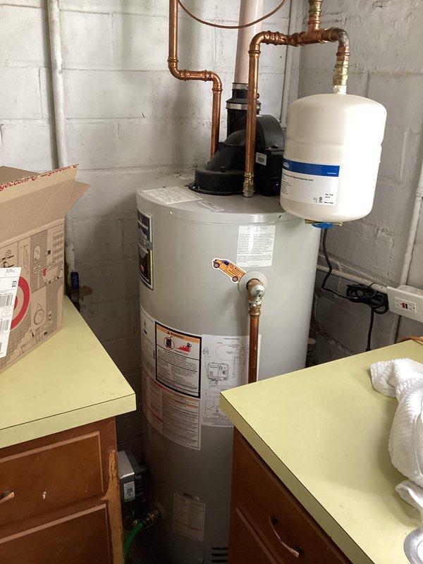 Completed scheduled maintenance flush and fill procedure on residential tanked water heater located in basement utility area. Drained sediment buildup from tank bottom, flushed system thoroughly to remove mineral deposits and debris, then refilled unit to restore proper operation. Inspected all associated plumbing connections, including copper supply lines, brass valves, expansion tank, and circulator pumps. Verified proper function of blue-handled ball valve and all shut-off points. System tested and confirmed operational upon completion of maintenance service.