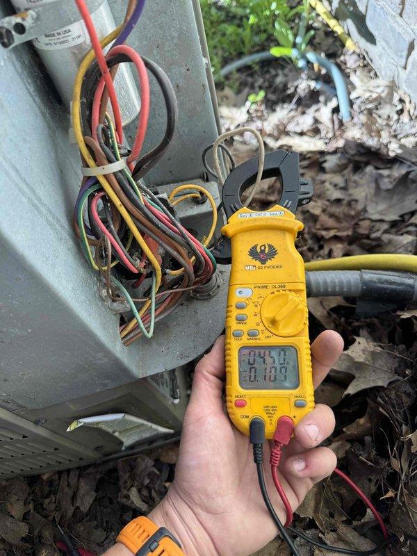 Completed preventive maintenance service on two outdoor air conditioning condensing units as part of recurring cooling season maintenance program. Performed comprehensive electrical diagnostics on both systems using digital multimeter and clamp meter to verify proper voltage, amperage, and electrical connections. Inspected wiring harnesses and terminal connections at junction boxes, noting multiple wire bundles with various color-coded conductors. Measured electrical readings on both units to ensure systems operating within manufacturer specifications. Opened access panels to examine internal components and wiring configurations. Observed accumulated debris and outdoor weathering on equipment housings. Both twin AC systems tested and found operational following standard maintenance protocols.