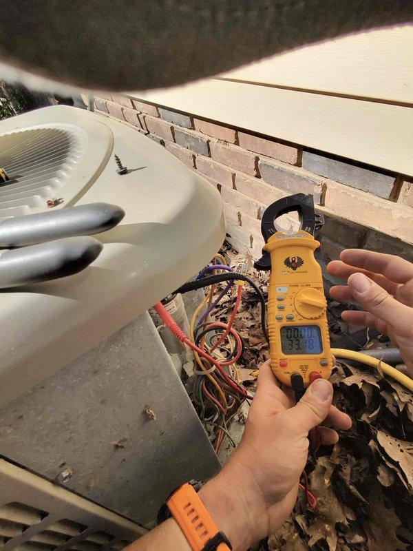Completed preventive maintenance service on two outdoor air conditioning condensing units as part of recurring cooling season maintenance program. Performed comprehensive electrical diagnostics on both systems using digital multimeter and clamp meter to verify proper voltage, amperage, and electrical connections. Inspected wiring harnesses and terminal connections at junction boxes, noting multiple wire bundles with various color-coded conductors. Measured electrical readings on both units to ensure systems operating within manufacturer specifications. Opened access panels to examine internal components and wiring configurations. Observed accumulated debris and outdoor weathering on equipment housings. Both twin AC systems tested and found operational following standard maintenance protocols.