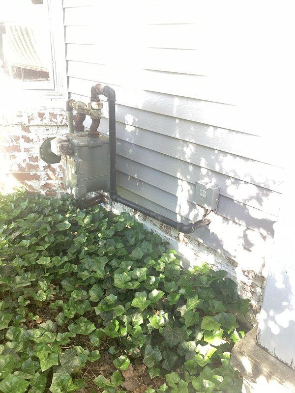 Conducted comprehensive site evaluation for whole home generator installation at residential property. Assessed existing electrical infrastructure including gas meter location and utility connections on exterior wall. Documented optimal generator placement location on side yard, determining proper clearances of 2 feet from home structure and 3 feet from window opening to meet manufacturer specifications and local code requirements. Evaluated existing gas service accessibility and routing options for fuel supply connection. Photographed installation site conditions including foundation area, exterior siding, existing utility penetrations, and surrounding vegetation that may require trimming for proper clearance. Identified suitable location on grassy area adjacent to building with adequate access for equipment delivery and future maintenance. Assessed electrical panel accessibility for transfer switch integration and main service disconnect coordination. Documented site conditions inclu