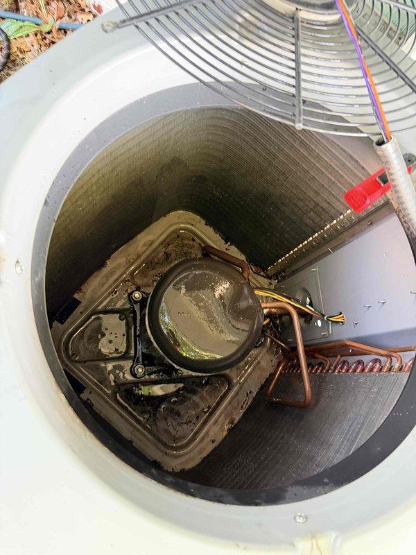 Completed comprehensive cooling system maintenance on residential HVAC unit located in basement mechanical room. Performed thorough inspection of condenser unit, which showed significant dirt and debris accumulation on fan motor assembly and interior surfaces. Cleaned condenser coils, fan blades, and housing to restore optimal airflow and heat transfer efficiency. Verified electrical connections at terminal blocks, inspected refrigerant lines for proper insulation and potential leaks, and confirmed all copper tubing connections were secure. Removed organic debris from fan guard and surrounding areas. System tested and operating within normal parameters following maintenance procedures.