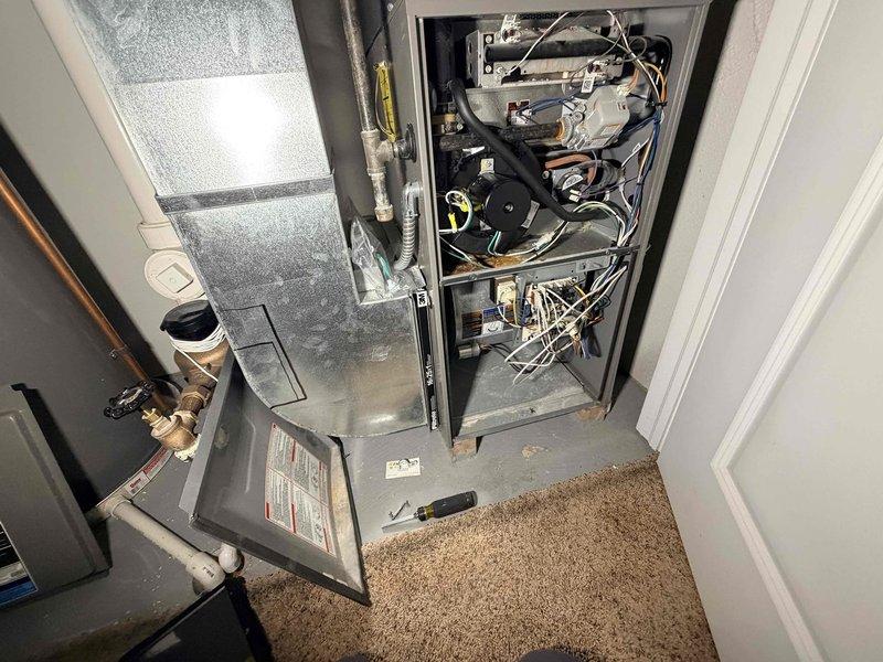 Responded to no cooling call on aging HVAC system. Upon arrival, confirmed unit was running but not producing cool air. Opened air handler access panel to inspect internal components, checked electrical connections, blower motor assembly, and wiring. Examined refrigerant lines, condensate drain system with PVC T-junction and copper drain extension, and verified proper drainage function. Documented system condition with photos showing air handler configuration, ductwork connections, and drainage components for service records.