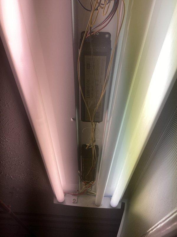 Conducted comprehensive electrical inspection of residential property. Inspected exterior Tesla wall-mounted electrical equipment installation at foundation level near glass block window, verifying proper placement and connection integrity. Performed interior evaluation of fluorescent lighting fixture, examining ballast operation, wiring connections, and tube functionality across three-lamp configuration.