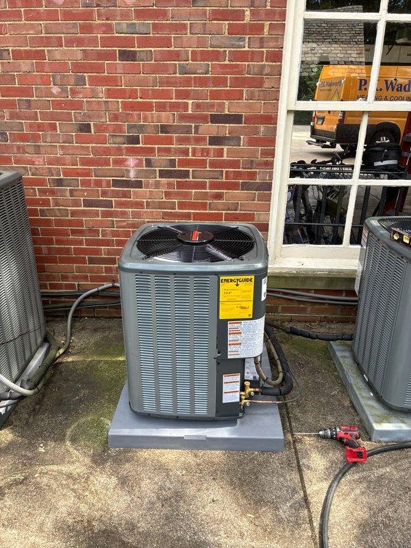 Completed installation of new air conditioning condenser unit on existing concrete pad against exterior brick wall. Unit was positioned centrally between two existing HVAC systems, with proper clearance maintained for airflow and serviceability. Connected refrigerant lines and electrical service to new condenser, verified all manufacturer labels and warning stickers were properly affixed and visible. Performed system startup procedures and utilized Fieldpiece SMAN digital manifold gauge set to measure and record refrigerant pressures, superheat, and subcooling values. All readings confirmed system operating within manufacturer specifications. New AC unit fully operational and ready for service.