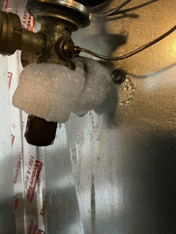 Responded to no cooling complaint and found evaporator coil completely frozen with significant ice buildup on refrigerant lines and valve assembly. Diagnosed restricted airflow due to severely clogged air filter and dirty evaporator coil fins. Shut down system to allow ice to thaw, replaced air filter, and cleaned evaporator coil. System restored to normal operation with proper airflow and cooling capacity.