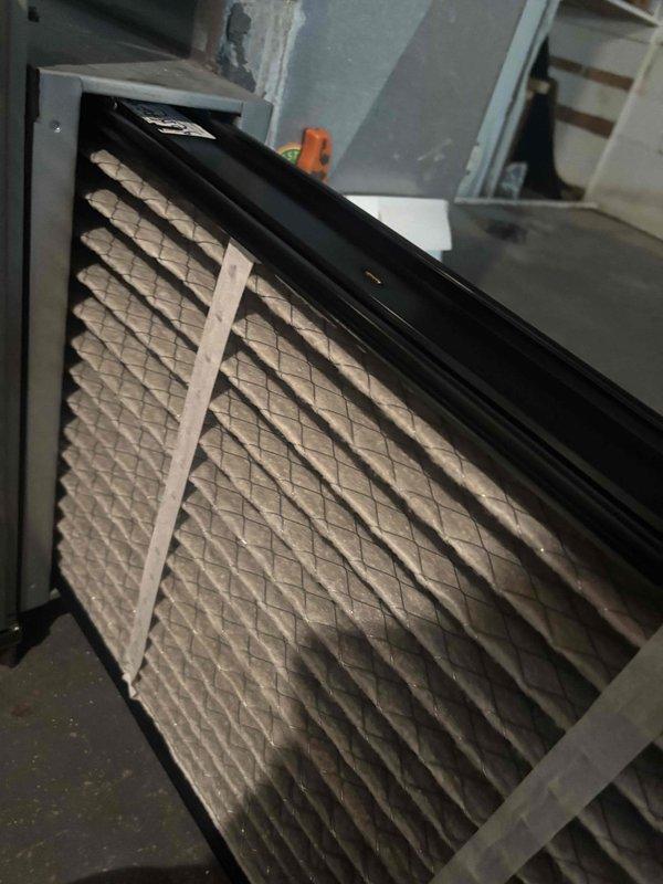 Completed scheduled preventive maintenance service on window-mounted HVAC cooling system. Performed comprehensive system inspection including examination of air filter, ductwork connections, and electrical components. Filter showed moderate dust and debris accumulation consistent with normal operation; documented current condition with photographs for maintenance records. Verified proper installation of pleated air filter within metal housing frame and confirmed secure mounting. Inspected internal ductwork insulation, metal framework, and control wiring including power and control circuits. All electrical connections, including blue, red, and yellow control wires, were found to be properly secured and routed. System components, ductwork, and access panels were in satisfactory operating condition with no immediate service needs identified.
