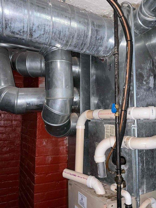 Completed full HVAC system installation including 96% efficiency furnace and air conditioning system. Rigging equipment was utilized to hoist outdoor condensing unit 10-15 feet to rooftop location. Post-installation testing performed using digital manometer to verify proper static pressure readings across the system, with measurements showing 0.39 inWG and -0.61 inWG differential. New galvanized ductwork installed in basement mechanical room with proper connections and transitions to existing infrastructure.