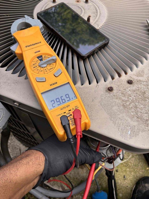 Completed routine cooling maintenance on residential air conditioning system. Inspected outdoor condenser unit and found accumulated dirt and debris between evaporator coil fins, which was cleaned to restore proper airflow and heat transfer efficiency. Performed electrical diagnostics using clamp meter to verify system amperage and confirm compressor operation within manufacturer specifications, with readings indicating normal performance at 296.9 amps. All components inspected and system operating properly upon completion.