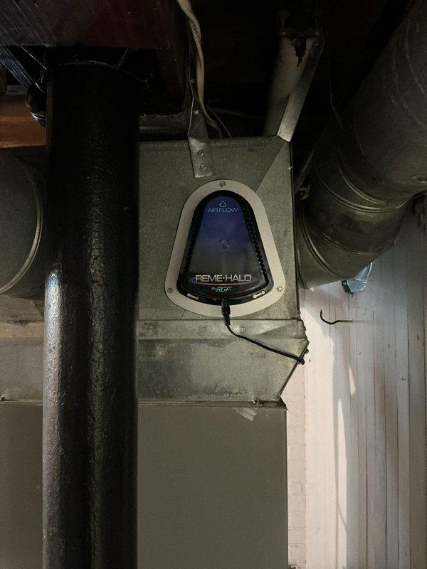 Responded to no cooling complaint on 10-15 year old electric central air system. Upon inspection, found blower motor operational but insufficient airflow distribution throughout residence. Verified blower motor assembly and ductwork connections in basement air handler unit. System equipped with REME HALO air purification device showing proper airflow readings on digital display. Assessed blower wheel, motor wiring connections, and ventilation components for proper operation.