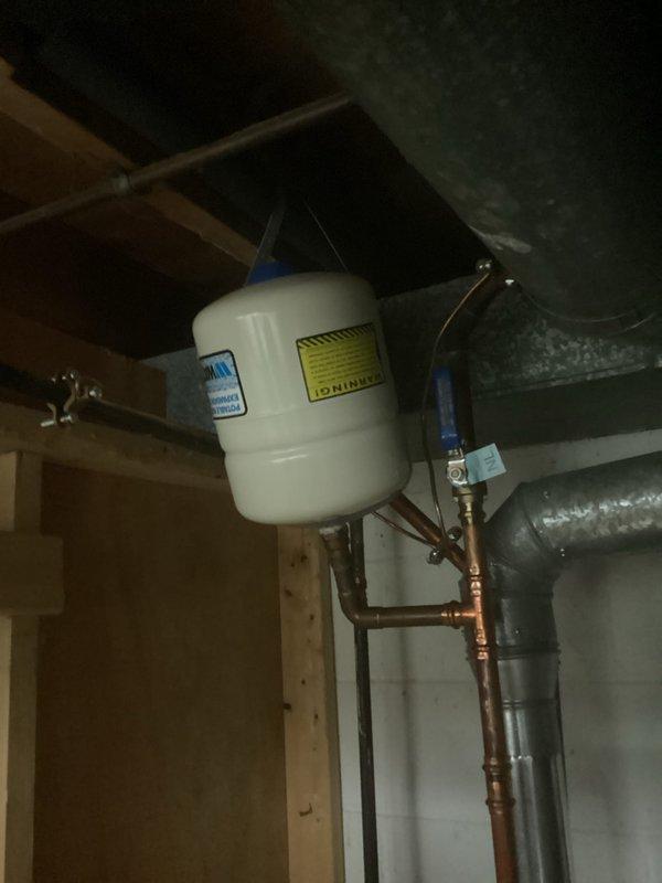Completed afternoon electrical inspection of residential property. Documented electrical panel configuration showing multiple 20-amp circuit breakers with proper wire terminations and color-coded conductors. Also photographed hydronic heating system components in basement area, including expansion tank with pressure relief valve and associated copper piping with shutoff valves, to verify electrical and mechanical systems integration for compliance purposes.