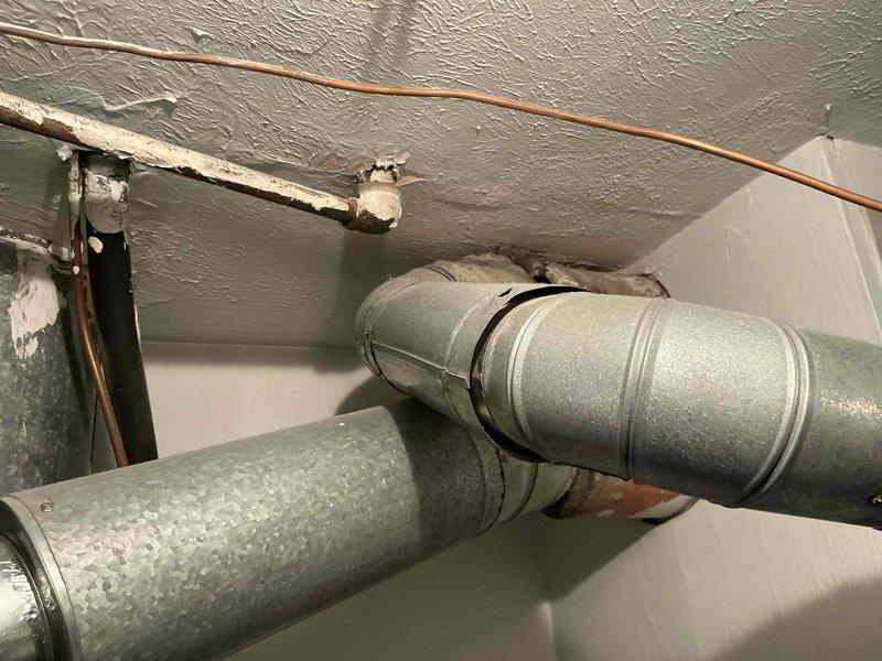 Conducted comprehensive site evaluation for full HVAC system replacement. Assessed existing outdoor condensing unit installed on concrete pad adjacent to building exterior and inspected interior ductwork system including galvanized metal supply ducts mounted to basement ceiling joists. Documented current equipment condition, installation configuration, and structural mounting points to provide customer with complete system replacement options and specifications.