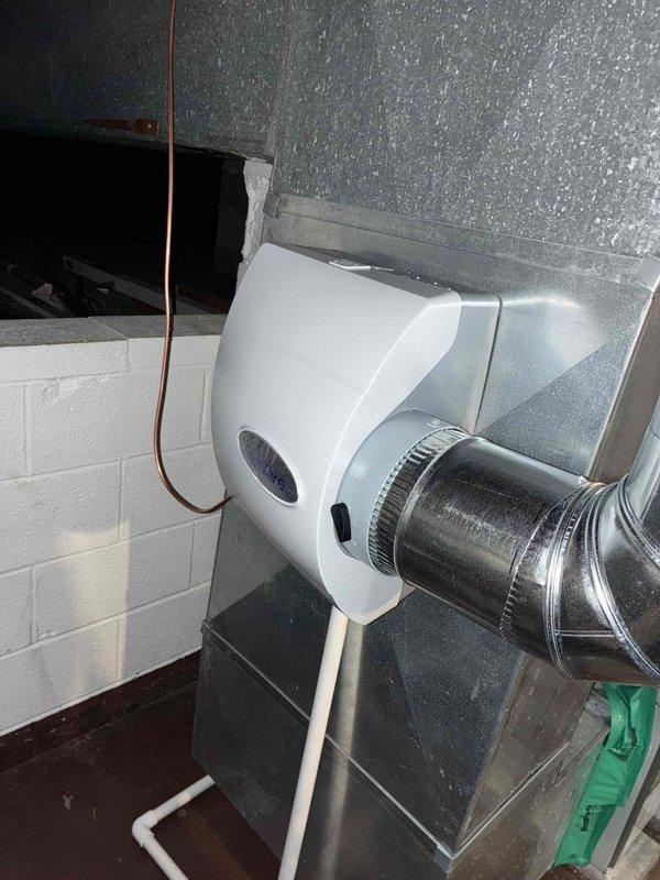 Completed installation of new air conditioning system including outdoor condensing unit with DiversiTech disconnect box mounted on exterior brick wall, whole-home humidifier unit installed in mechanical space with proper ductwork connection, and air scrubber system. All equipment properly wired, tested, and operational with financing arranged for customer.