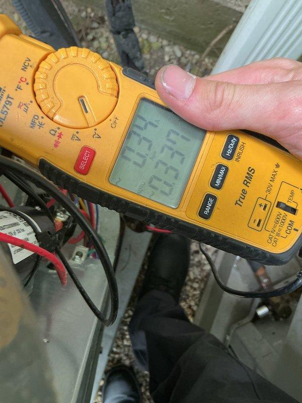 Completed HVAC cooling system maintenance inspection and electrical diagnostics. Verified system voltage readings at 23.3V using digital multimeter and inspected capacitor connections and terminals. Documented water heater and expansion tank installation in mechanical area, noting existing plumbing configuration and copper piping connections for reference during cooling system evaluation.