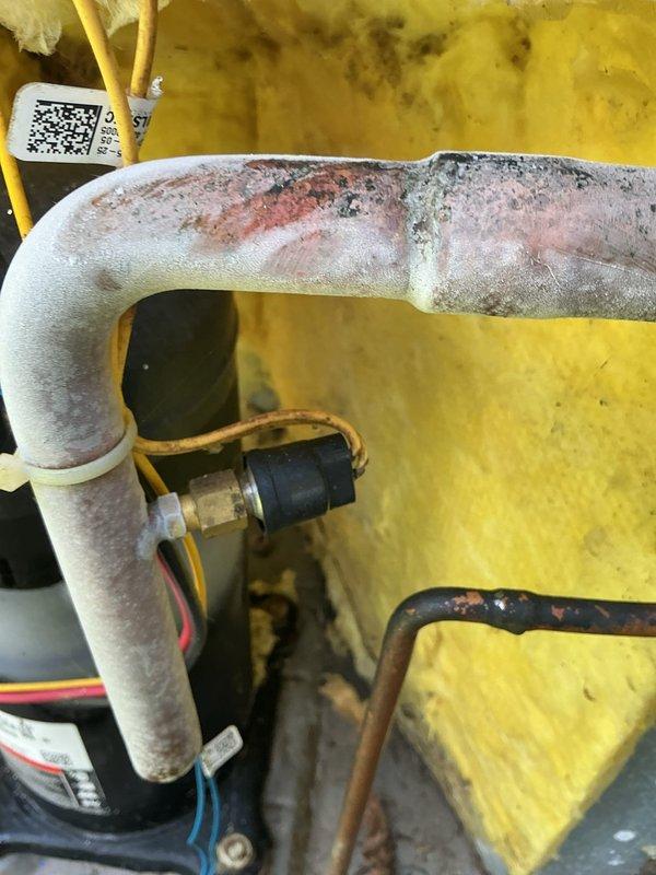 Responded to service call for air conditioning unit cycling off after thirty seconds of operation. Upon inspection, found heavy frost and ice buildup on suction line and compressor, indicating restricted refrigerant flow or low charge condition. Performed diagnostic testing with multimeter to verify system operation and electrical components. Identified refrigerant system issue causing inadequate cooling and short cycling. Documented conditions with photographs showing frosted refrigerant lines, compressor assembly, and internal cabinet components for service records.