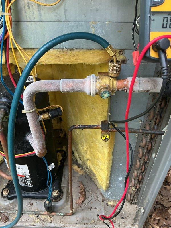 Responded to service call for air conditioning unit cycling off after thirty seconds of operation. Upon inspection, found heavy frost and ice buildup on suction line and compressor, indicating restricted refrigerant flow or low charge condition. Performed diagnostic testing with multimeter to verify system operation and electrical components. Identified refrigerant system issue causing inadequate cooling and short cycling. Documented conditions with photographs showing frosted refrigerant lines, compressor assembly, and internal cabinet components for service records.
