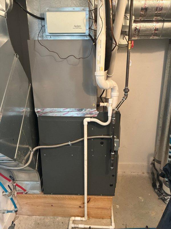 Completed installation of a 96% high-efficiency furnace system in basement utility area. Unit was mounted on wooden platform with proper clearances, including connection of gas line via flexible conduit, installation of white PVC venting and condensate drain system with proper pitch, integration of metal supply and return ductwork with professional sealing, and complete electrical wiring to wall-mounted air handler control box. System was tested for proper operation and all safety protocols were verified upon completion.