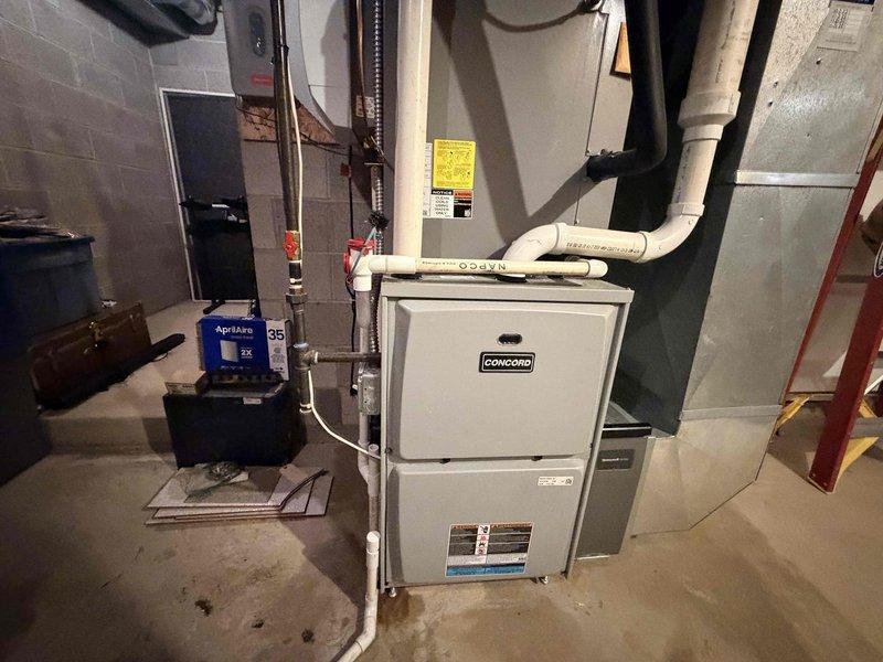 Responded to customer report of furnace leak following recent system check. Upon arrival, performed thorough inspection of Concord furnace unit and associated plumbing connections. Examined condensate drain system, humidifier connections, and all water supply lines to heating equipment. Inspected PVC condensate piping, copper water lines with shut-off valves, and Aprilaire humidifier installation for signs of active leakage or moisture accumulation. Documented equipment conditions and plumbing connections with photographs for service records.