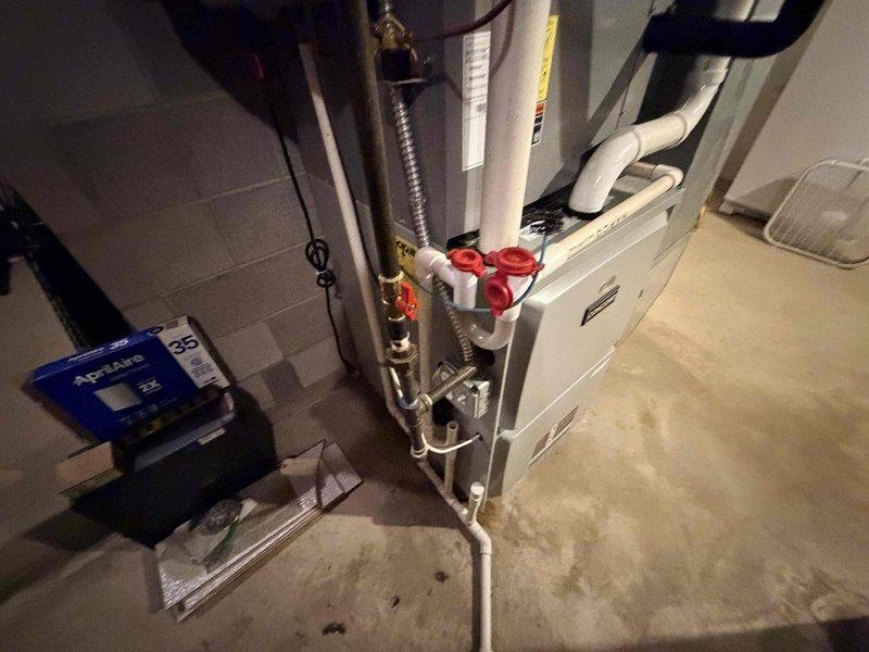 Responded to customer report of furnace leak following recent system check. Upon arrival, performed thorough inspection of Concord furnace unit and associated plumbing connections. Examined condensate drain system, humidifier connections, and all water supply lines to heating equipment. Inspected PVC condensate piping, copper water lines with shut-off valves, and Aprilaire humidifier installation for signs of active leakage or moisture accumulation. Documented equipment conditions and plumbing connections with photographs for service records.