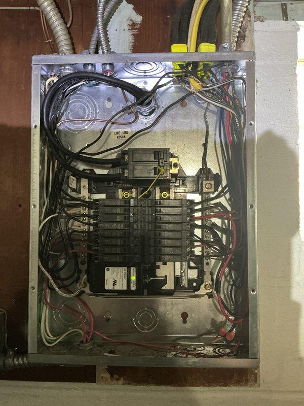 Conducted electrical site visit to inspect and document existing electrical panel and utility room conditions. Photographed main electrical panel showing circuit breaker configuration, internal wiring connections, and conduit entry points for service records. Documented water heater installation and associated electrical/plumbing infrastructure in basement utility area.