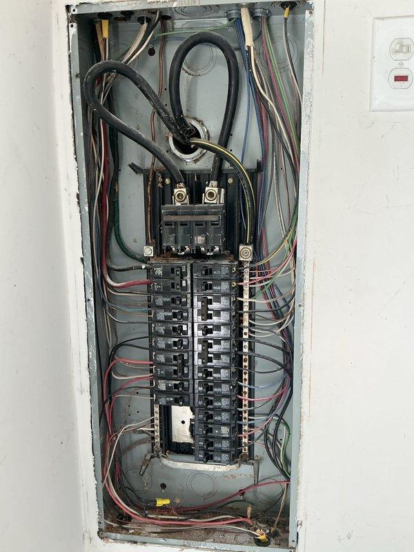 Conducted comprehensive electrical inspection of residential service panel and associated systems. Documented panel configuration showing proper circuit breaker arrangement, main disconnect connections, and wire routing throughout the enclosure. Verified neutral and ground bus bar installations, assessed wire management and securing methods, and confirmed GFCI outlet protection adjacent to panel location. Inspected utility area electrical and plumbing infrastructure, including outlet placement and cable routing in confined corner space near copper supply lines and shut-off valves.