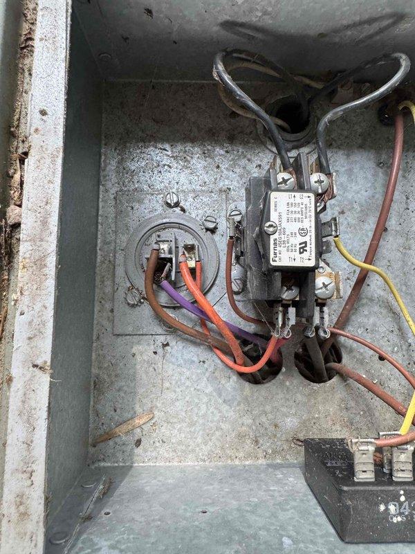 # HVAC Service Call - No Cooling Condition

Responded to service call for central air conditioning system over 15 years old experiencing inadequate cooling performance during high temperature and humidity conditions, with complete loss of cooling at time of arrival.

Upon inspection, found outdoor condensing unit in severely deteriorated condition with extensive dirt and debris accumulation throughout. Condenser coil heavily clogged with organic matter, dirt, and environmental debris significantly restricting airflow and reducing heat transfer capability. External surfaces showed advanced weathering, oxidation, and corrosion consistent with age and lack of routine maintenance.

Examined electrical components within contactor panel. Found weathered electrical enclosure with visible surface corrosion and grime buildup. Inspected contactor relay and associated wiring connections including multiple conductor terminations. Electrical components showed signs of aging and environmental exposu