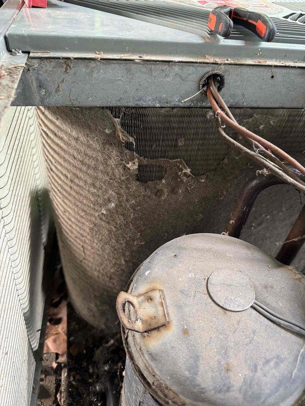 # HVAC Service Call - No Cooling Condition

Responded to service call for central air conditioning system over 15 years old experiencing inadequate cooling performance during high temperature and humidity conditions, with complete loss of cooling at time of arrival.

Upon inspection, found outdoor condensing unit in severely deteriorated condition with extensive dirt and debris accumulation throughout. Condenser coil heavily clogged with organic matter, dirt, and environmental debris significantly restricting airflow and reducing heat transfer capability. External surfaces showed advanced weathering, oxidation, and corrosion consistent with age and lack of routine maintenance.

Examined electrical components within contactor panel. Found weathered electrical enclosure with visible surface corrosion and grime buildup. Inspected contactor relay and associated wiring connections including multiple conductor terminations. Electrical components showed signs of aging and environmental exposu