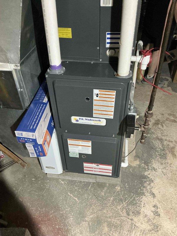 Conducted HVAC system estimate for residential furnace replacement. Documented existing gray-painted vertical furnace unit with dual white PVC venting system, evaluated current installation including electrical panel configuration, refrigerant line routing, and drainage system components. Assessed equipment accessibility and provided replacement options for customer consideration.