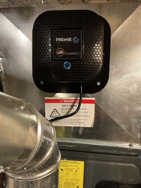Responded to emergency service call for non-operational air conditioning system. Upon inspection, verified HVAC system functionality including furnace, air handler, and ductwork components. Confirmed proper operation of installed PREMIE UV-C air purification system with active blue indicator light functioning correctly within the duct system.