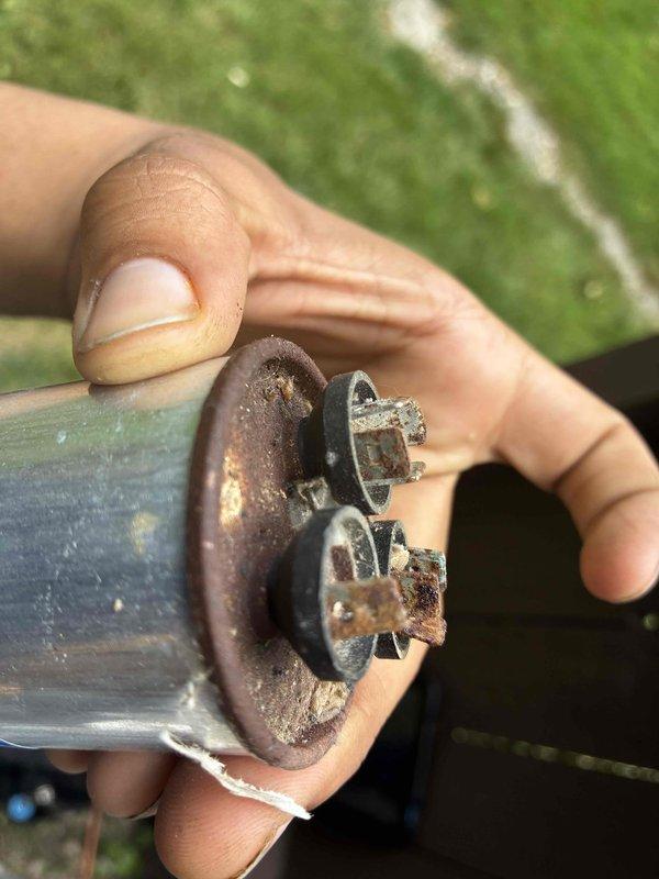 Responded to no cooling complaint affecting entire home. Upon inspection, discovered failed dual run capacitor with severe rust and corrosion on terminals and mounting bracket. Removed defective capacitor and installed new replacement unit. Verified proper amperage draw and system operation using clamp meter, confirming compressor and condenser fan motor running within manufacturer specifications. System restored to normal cooling operation.