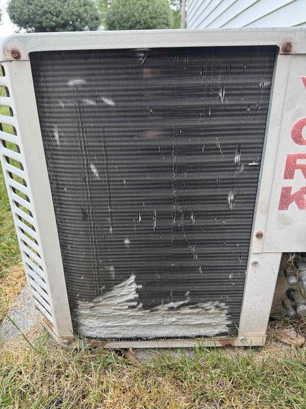 Performed comprehensive AC tune-up on 34-year-old cooling system. Removed heavy debris accumulation including lint, cottonwood seeds, and outdoor matter from condenser coil grille that was restricting airflow. Cleaned condenser coils, inspected electrical connections at disconnect box, checked refrigerant levels, tested fan motor operation, and verified system cooling capacity. Unit operational and running efficiently after maintenance despite age-related wear and minor rust on housing.