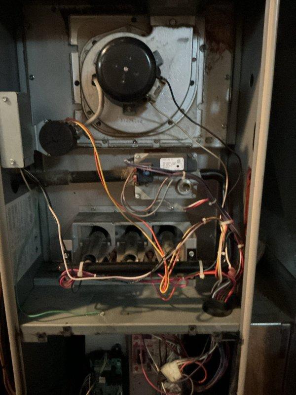 Responded to emergency no-cooling call and performed diagnostic inspection of residential HVAC system. Upon accessing the unit and removing panels, conducted thorough examination of internal components including blower motor assembly, electrical connections, and control board. Inspected wiring throughout the system, noting multiple wire connections between furnace components and air conditioning controls. Evaluated capacitor, control module, and associated electrical components for proper operation. Documented system condition with photographs showing internal cabinet layout, blower assembly, and electrical control components for service records.
