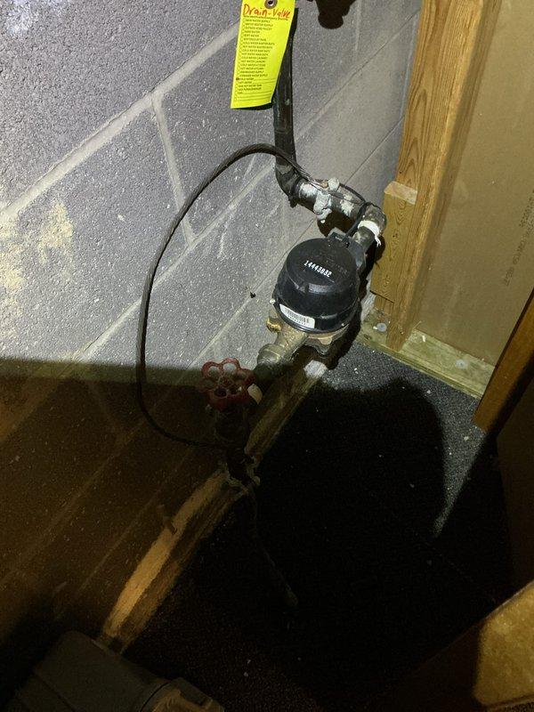 Conducted mid-morning electrical inspection of residential service panel and utility systems. Documented existing electrical panel configuration showing dual-column breaker arrangement with approximately 20-24 circuit breakers, verified proper wire management and connections to bus bars, and confirmed organized installation of branch circuits. Also photographed adjacent plumbing assembly with water meter/pressure regulator and shutoff valve for reference during inspection.