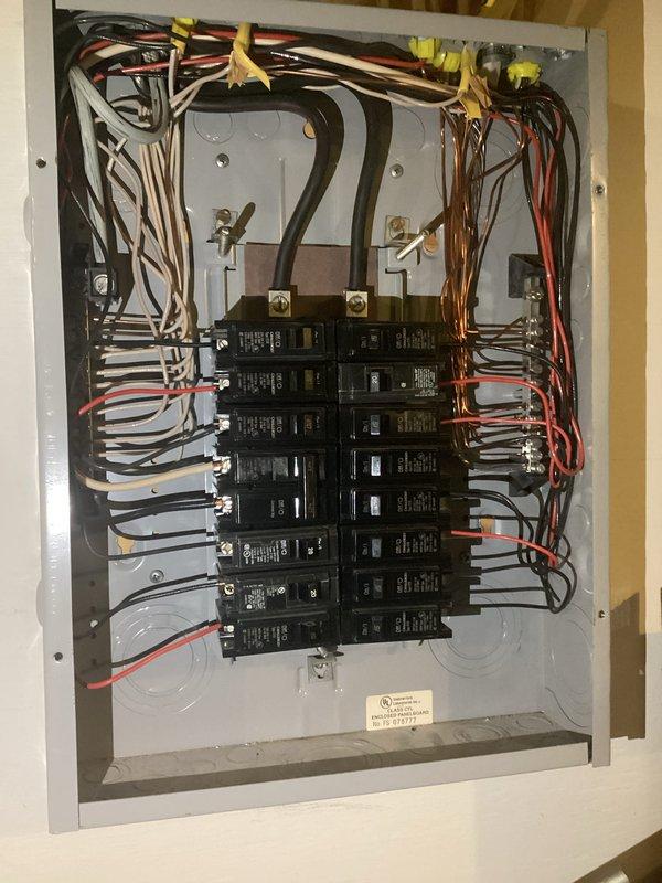 Completed comprehensive electrical inspection of residential service panel and exterior HVAC electrical components. Interior panel inspection revealed properly organized circuit breaker configuration with appropriate wire management, yellow wire connectors at service entry point, and all breakers securely mounted in dual rows. Exterior inspection documented HVAC disconnect and associated refrigerant line insulation with electrical conduit connections to outdoor unit, confirming proper installation and weatherproofing of exterior electrical components.