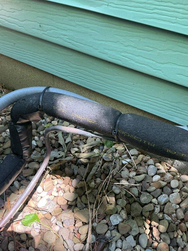 Responded to no cooling complaint on residential AC system installed in May 2023. Upon arrival, discovered refrigerant line insulation had deteriorated significantly, with foam sleeve showing severe weathering and breakdown at the foundation penetration point. The compromised insulation was allowing heat transfer to the suction line, reducing system efficiency and cooling capacity. Assessed the line set penetration through the building exterior, noting inadequate sealing at the entry point. Documented the condition of the deteriorated insulation sleeve and penetration seal for replacement recommendation. System requires new line set insulation and proper sealing of the wall penetration to restore full cooling performance and prevent further efficiency loss.
