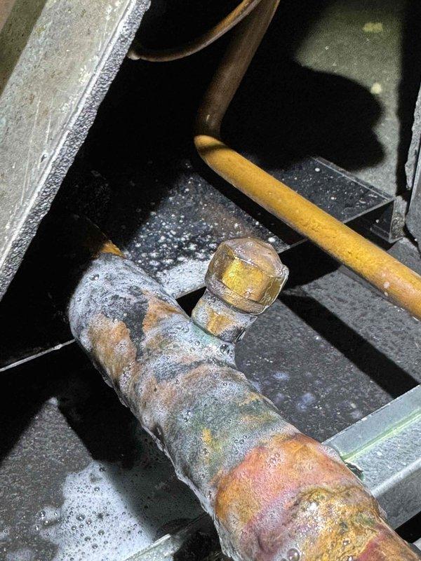 Returned to property to perform comprehensive refrigerant leak search on Unico System air handler located in attic space. Upon inspection, discovered significant frost and ice accumulation on suction line, indicating active refrigerant leak and loss of system charge. Conducted thorough leak detection procedures, identifying leak location on copper refrigerant piping. Documented frost buildup and system conditions with photographic evidence for service records.