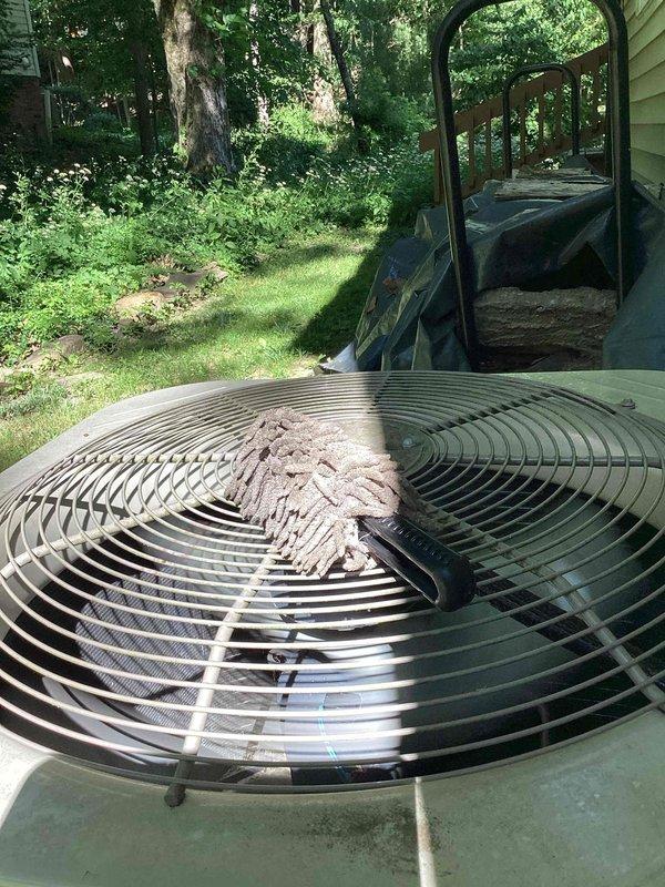# HVAC Maintenance - Cooling System Service

Performed routine maintenance inspection on residential Unico cooling system. Upon arrival, observed outdoor condensing unit with debris accumulation on top fan grille, including dried leaves and dirt buildup. Unit exterior showed weathered olive-green paint finish, positioned on concrete pad in shaded backyard environment with mature tree coverage.

Conducted thorough inspection of electrical components within outdoor unit. Examined capacitor, contactor assembly, and associated wiring connections. Noted electrical panel showing signs of age and environmental exposure with worn paint, surface corrosion, and dirt accumulation. Verified proper wire connections including multiple colored conductors (blue, yellow, brown, red, and green) with wire nuts and terminals. Inspected mounting hardware and electrical fittings for secure installation.

Cleared debris from fan grille to ensure proper airflow and prevent potential restriction to condenser o