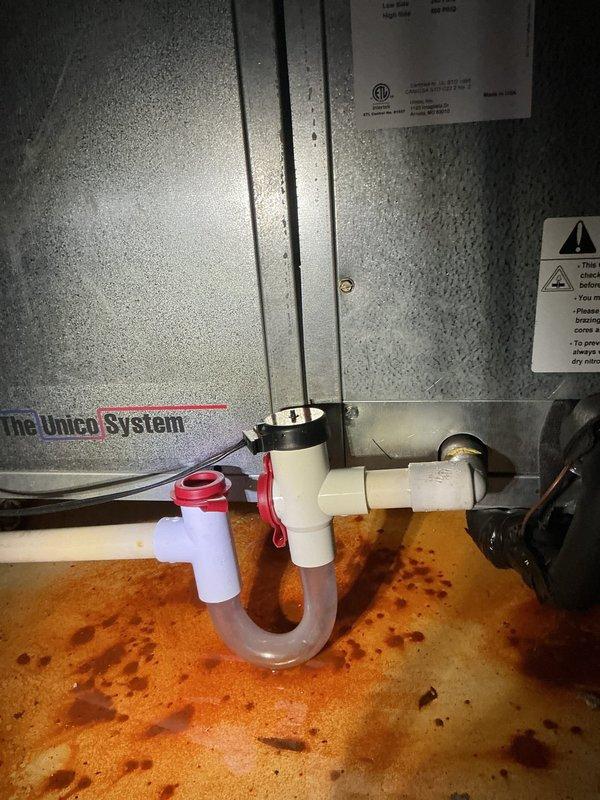 Performed HVAC service call on air conditioning system. Inspected air handler unit and condensate drainage system. Found standing water in drain pan with visible staining and discoloration indicating drainage issues. Examined PVC condensate line configuration with trap assembly. Noted significant rust-colored mineral deposits and water staining on drain pan surface. Documented moisture accumulation and high humidity conditions within cabinet. Tested and evaluated drainage components including trap assembly and discharge piping. System components assessed for proper operation and water removal functionality.