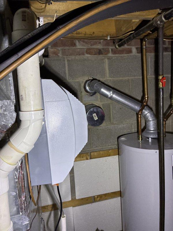 Provided HVAC replacement estimate options for air conditioning system. Furnace had been previously replaced. Documented existing Trane outdoor condensing unit installation on concrete pad with proper electrical conduit routing, as well as basement mechanical components including copper refrigerant lines, PVC drainage system, and water heater configuration to assess replacement requirements and system compatibility.