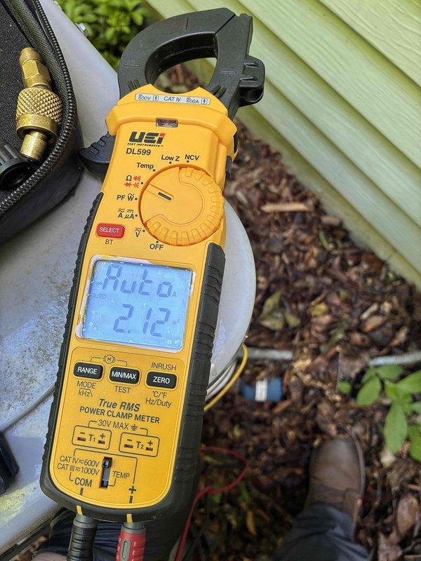 Completed comprehensive cooling system maintenance and performance verification. Utilized digital clamp meter to measure system amperage at 9.83 amps and recorded outdoor ambient temperature of 212°F, confirming proper electrical draw and documenting operating conditions for baseline performance data.