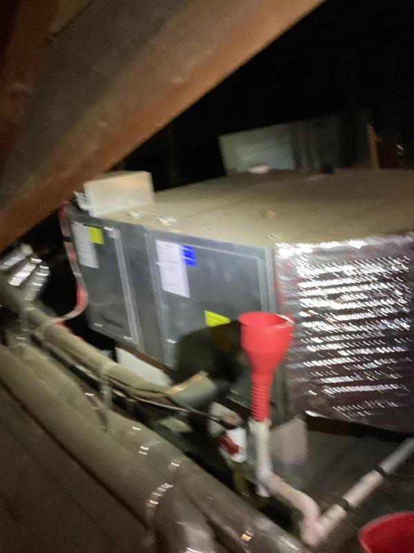 # HVAC Cooling Maintenance Summary

Completed scheduled preventive maintenance on residential air conditioning system located in attic space. Performed comprehensive inspection of air handling unit, verified proper operation of digital control system, and checked refrigerant lines and condensate drainage. Notable finding: observed frost accumulation on evaporator coil fins and refrigerant tubing, indicating potential airflow restriction or refrigerant charge issue requiring monitoring during future service visits.

# Detailed Work Performed

Accessed attic-mounted HVAC equipment and conducted thorough visual inspection of air handling unit and associated components. Verified digital control panel functionality with illuminated display showing active operation. Examined condensate drain lines (white PVC piping) for proper installation and drainage capability.

Inspected evaporator coil assembly, noting visible frost and ice accumulation on finned heat exchanger surfaces and refrigerant 