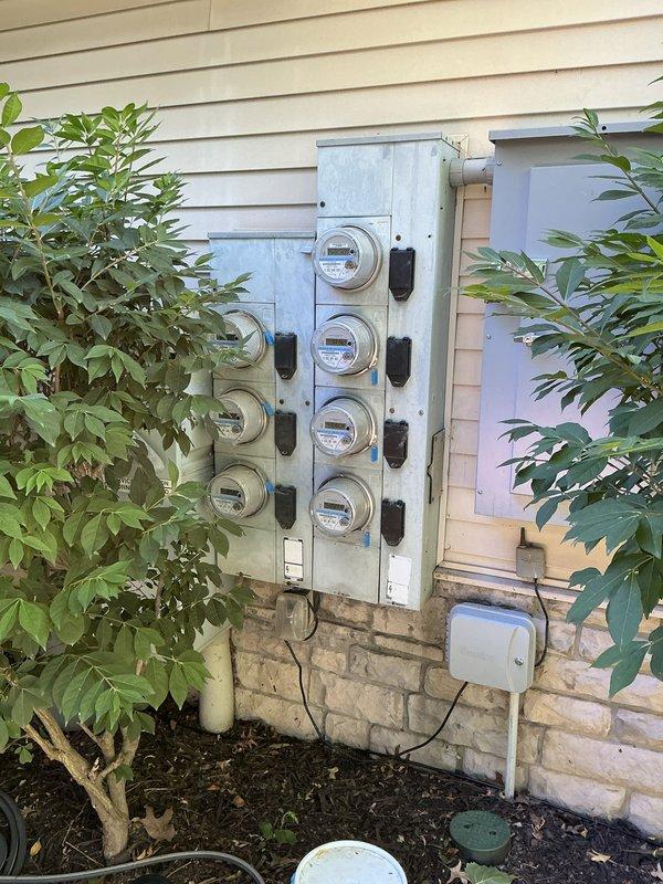 Performed comprehensive electrical inspection of multi-unit meter bank installation containing seven utility meters arranged in two wall-mounted panels. Documented existing conditions through photographic records, verifying proper meter placement, protective housing integrity, conduit connections, and associated disconnect switches for compliance and maintenance reference.