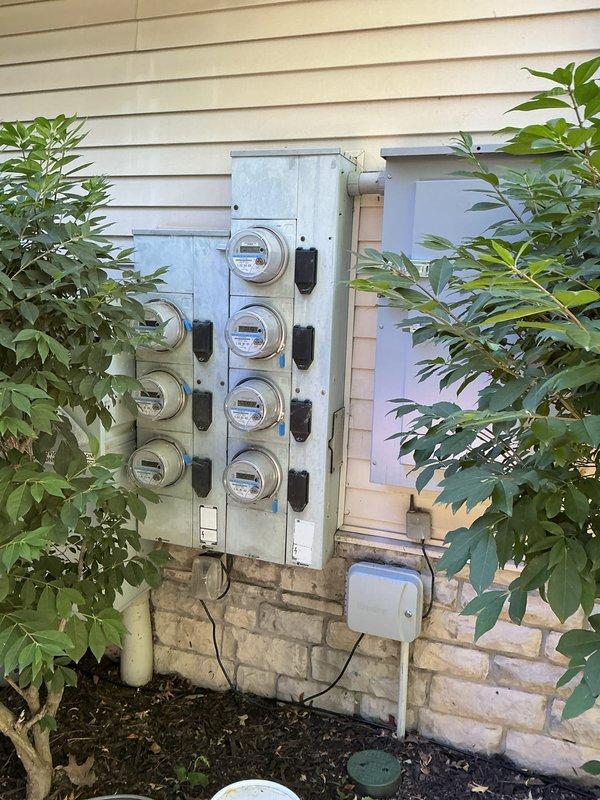 Performed comprehensive electrical inspection of multi-unit meter bank installation containing seven utility meters arranged in two wall-mounted panels. Documented existing conditions through photographic records, verifying proper meter placement, protective housing integrity, conduit connections, and associated disconnect switches for compliance and maintenance reference.