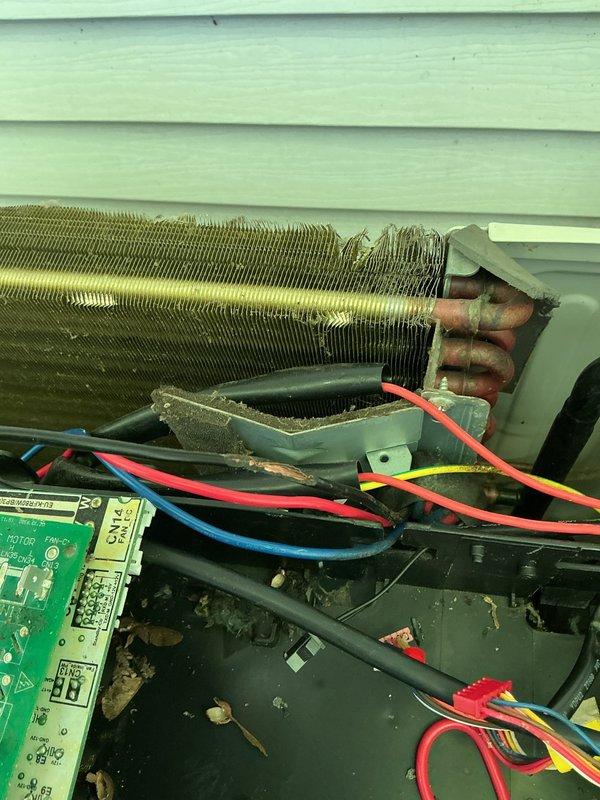 Responded to service call for 6-year-old Lennox mini-split system with rodent damage to electrical wiring. Upon arrival, inspected unit and confirmed mice had chewed through multiple wire connections affecting system operation. Customer reported circuit panel and control board had been previously replaced due to the same issue. Removed exterior panel to access internal components and assessed extent of damage to wiring harness, control board connections, and electrical pathways. Documented damaged coil section showing compression and deformation of fins, as well as accumulated debris throughout unit interior. Repaired and replaced compromised wiring connections using appropriate gauge wire and secure terminations. Cleaned debris from base compartment and verified all wire connections to green control board, capacitors, and component terminals were properly seated and secured. Tested system operation to ensure proper startup sequence and verified all electrical connections were function